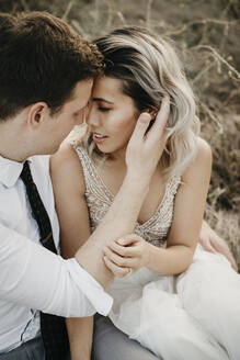 Affectionate bride and groom sitting outdoors - LHPF00768