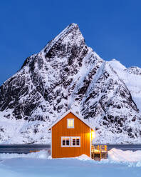 Gelbe Rorbuer-Hütte im Schnee bei Dämmerung, Sakrisoy, Moskenesoya, Lofoten, Nordland, Norwegen, Europa - RHPLF07311