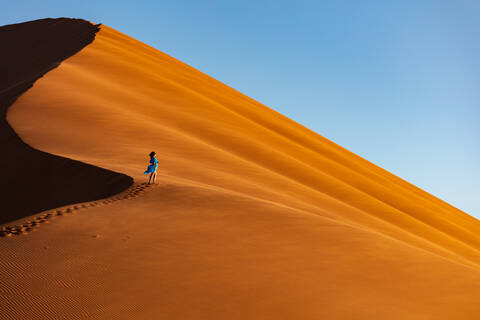 Drohnenaufnahme eines Modells, das die Düne 13 erklimmt, Sossusvlei, Namibia, Afrika, lizenzfreies Stockfoto