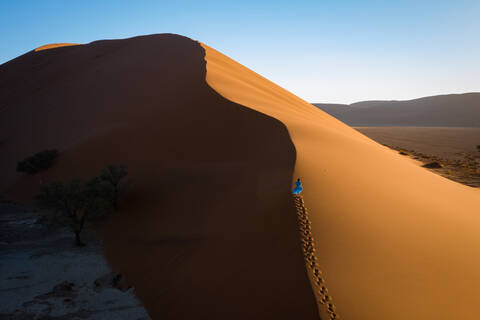 Drohnenaufnahme eines Modells, das die Düne 13 erklimmt, Sossusvlei, Namibia, Afrika, lizenzfreies Stockfoto