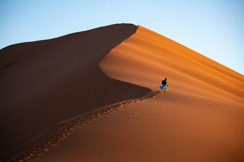 Aufnahme eines Models, das die Düne 13 mit einer Fotoausrüstung erklimmt, Sossusvlei, Namibia, Afrika - RHPLF07380