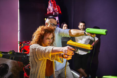 Freunde spielen und schießen mit Pistolen in einer Spielhalle, lizenzfreies Stockfoto