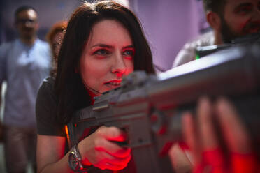 Fokussierte Frau schießt mit Gewehr in einer Spielhalle - ZEDF02609
