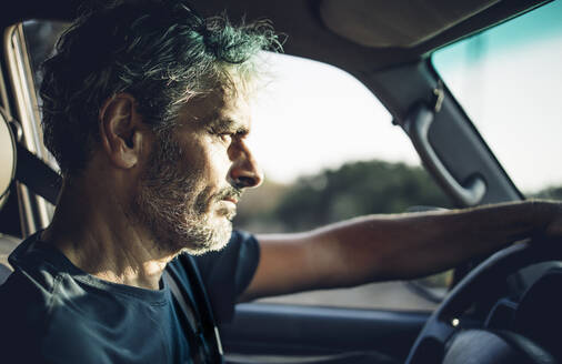 Mature man driving at sunset - OCMF00595