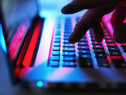 Man typing at his laptop computer at night - ABRF00527