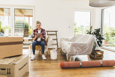 Woman moving into new home using tablet - UUF18852