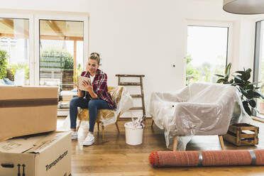 Woman moving into new home using tablet - UUF18853