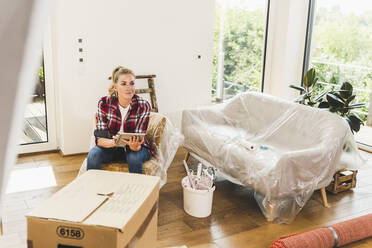 Woman moving into new home using tablet - UUF18855