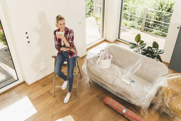 Woman moving into new home having a coffee break - UUF18861