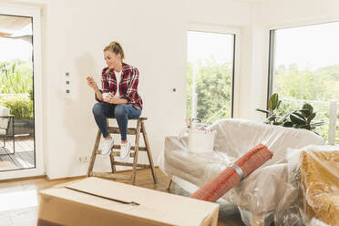 Woman moving into new home having a coffee break - UUF18862