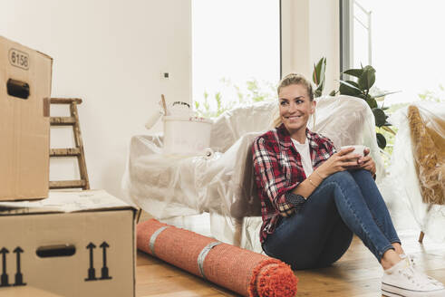 Woman moving into new home having a coffee break - UUF18864