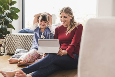 Glückliche Mutter und Tochter benutzen Tablet zu Hause, lizenzfreies Stockfoto