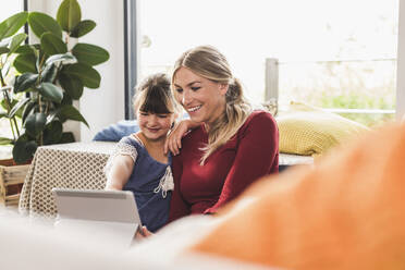 Happy mother and daughter using tablet at home - UUF18885