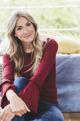 Portrait of smiling blond woman relaxing at home stock photo