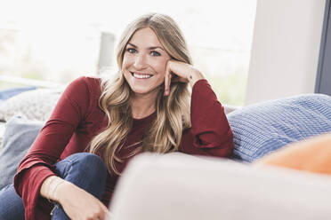 Portrait of smiling blond woman relaxing at home - UUF18927