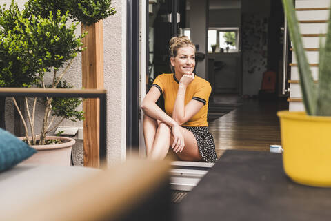 Relaxed woman sitting at terrace door at home stock photo