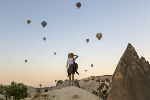 Junge Frau und Heißluftballons, Goreme, Kappadokien, Türkei, lizenzfreies Stockfoto