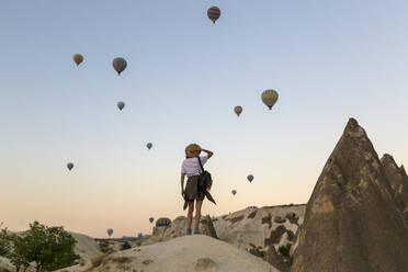 Young woman and hot air ballons, Goreme, Cappadocia, Turkey - KNTF03314
