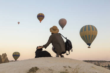 Young woman and hot air ballons, Goreme, Cappadocia, Turkey - KNTF03317