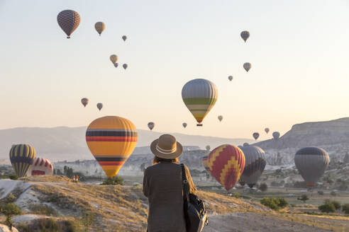 Young woman and hot air ballons, Goreme, Cappadocia, Turkey - KNTF03320