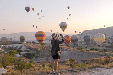 Junge Frau und Heißluftballons, Goreme, Kappadokien, Türkei, lizenzfreies Stockfoto