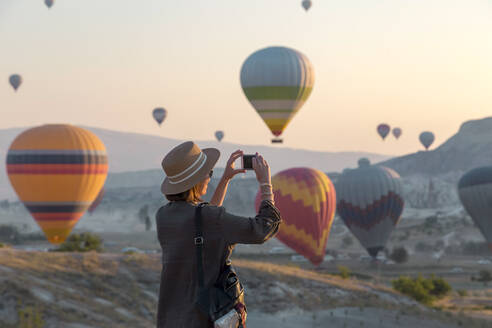 Young woman and hot air ballons, Goreme, Cappadocia, Turkey - KNTF03322