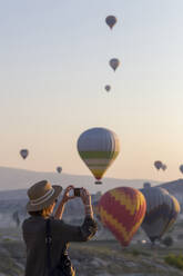 Young woman and hot air ballons, Goreme, Cappadocia, Turkey - KNTF03323