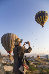 Young woman and hot air ballons, Goreme, Cappadocia, Turkey - KNTF03324