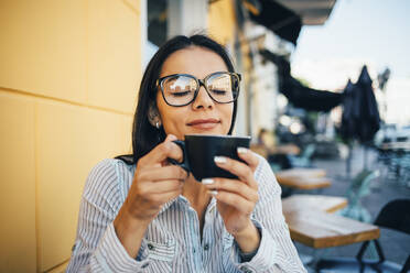 Young woman enjoying a cup of coffee in a cafe - OYF00044