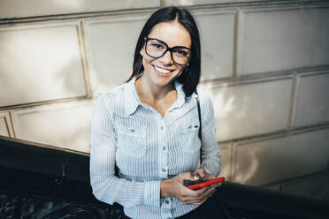 Portait of happy young businesswoman with cell phone outdoors - OYF00049