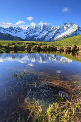 Schneebedeckte Gipfel und blauer Himmel spiegeln sich im Wasser bei Sonnenaufgang, Tombal, Soglio, Bergell, Kanton Graubünden, Schweiz, Europa - RHPLF07462