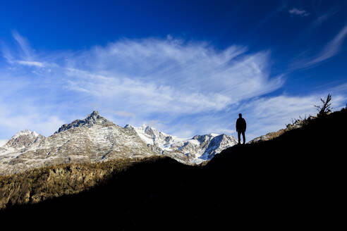 Hiker admires Monte Disgrazia from Lake Mufule, Malenco Valley, Province of Sondrio, Valtellina, Lombardy, Italy, Europe - RHPLF07501