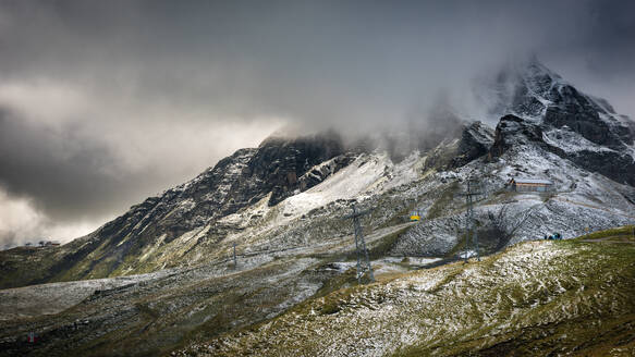 Eine gelbe Seilbahn in der Jungfrau unterhalb des in Schnee und Nebel gehüllten Gipfels von Tschuggen, Wallis, Schweiz, Europa - RHPLF07581