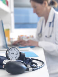 Health check, Doctor examining patients records after a consultation with the focus on a blood pressure gauge - ABRF00537