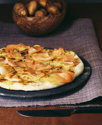 Nahaufnahme einer Pizza mit geräuchertem Lachs und Kartoffeln in einer Schüssel auf dem Tisch - PPXF00272