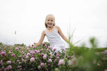 Smiling girl with bunches running on clover field - EYAF00385