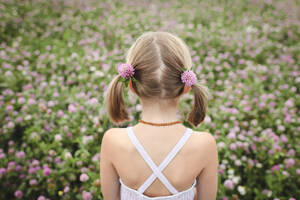 Rückansicht eines Mädchens mit Pferdeschwanz und Kleeblumen - EYAF00390