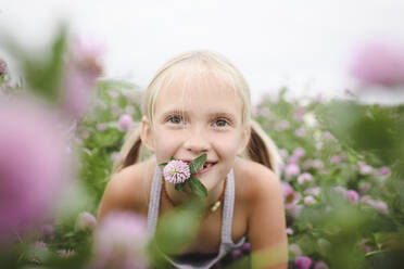 Porträt eines lächelnden Mädchens mit Kleeblume im Mund - EYAF00395