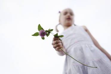 Lächelndes Mädchen mit Kleeblume in der Hand, von oben - EYAF00396