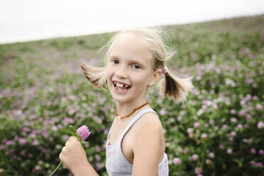 Laughing girl holding clover flowers - EYAF00397
