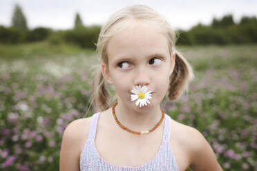 Girl with chamomile flower in her mouth - EYAF00403