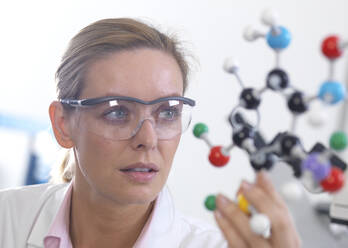 Scientist understanding a chemical formula using a ball and stick molecular model - ABRF00565