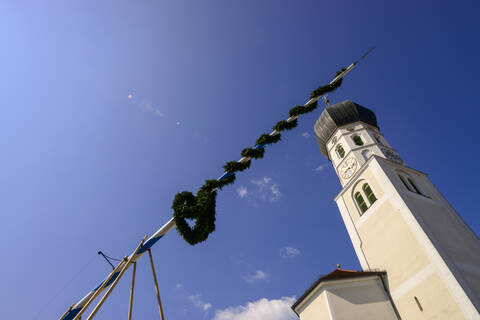 Niedriger Blickwinkel auf die Kirche St. Benedikt vor blauem Himmel an einem sonnigen Tag, Geretsried, Deutschland, lizenzfreies Stockfoto