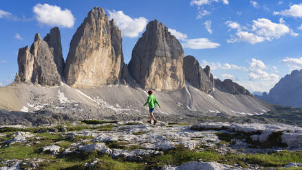 Boy walking on land against pinnacles at Tre Cime Di Lavaredo, Italy - LOMF00884