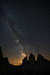 Landschaftliche Ansicht der Silhouette der Drei Zinnen vor einem nächtlichen Sternenfeld, Venetien, Italien - LOMF00896