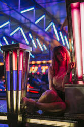 Junge Frau sitzt im Autoscooter auf einem Jahrmarkt bei Nacht - LJF00878