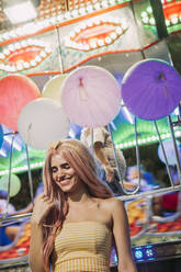 Happy young woman on a funfair at night - LJF00891