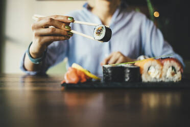 Nahaufnahme einer Frau, die in einem Restaurant Sushi isst - OYF00057