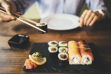 Nahaufnahme einer Frau, die in einem Restaurant Sushi isst - OYF00060