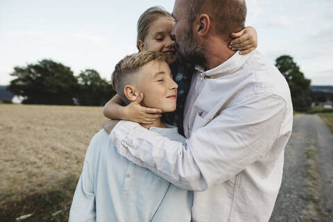 Affectionate father with two children outdoors stock photo